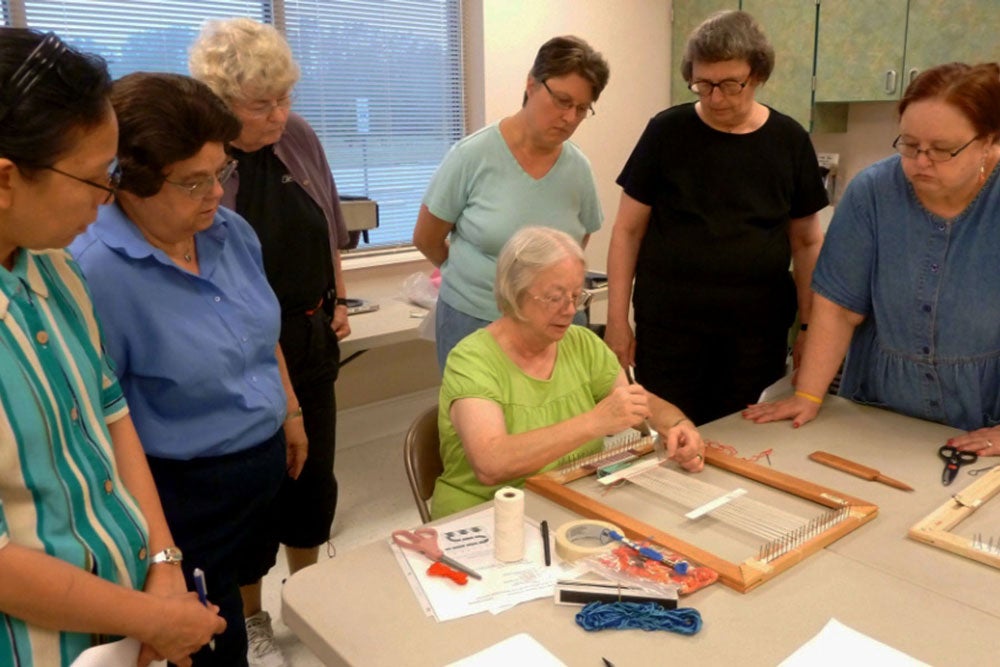Image of LLP weaving class instructor showing class participants how it's done